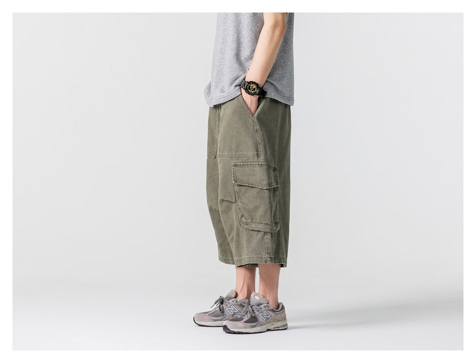 Side view of a model wearing loose olive cargo shorts with a large flap pocket.
