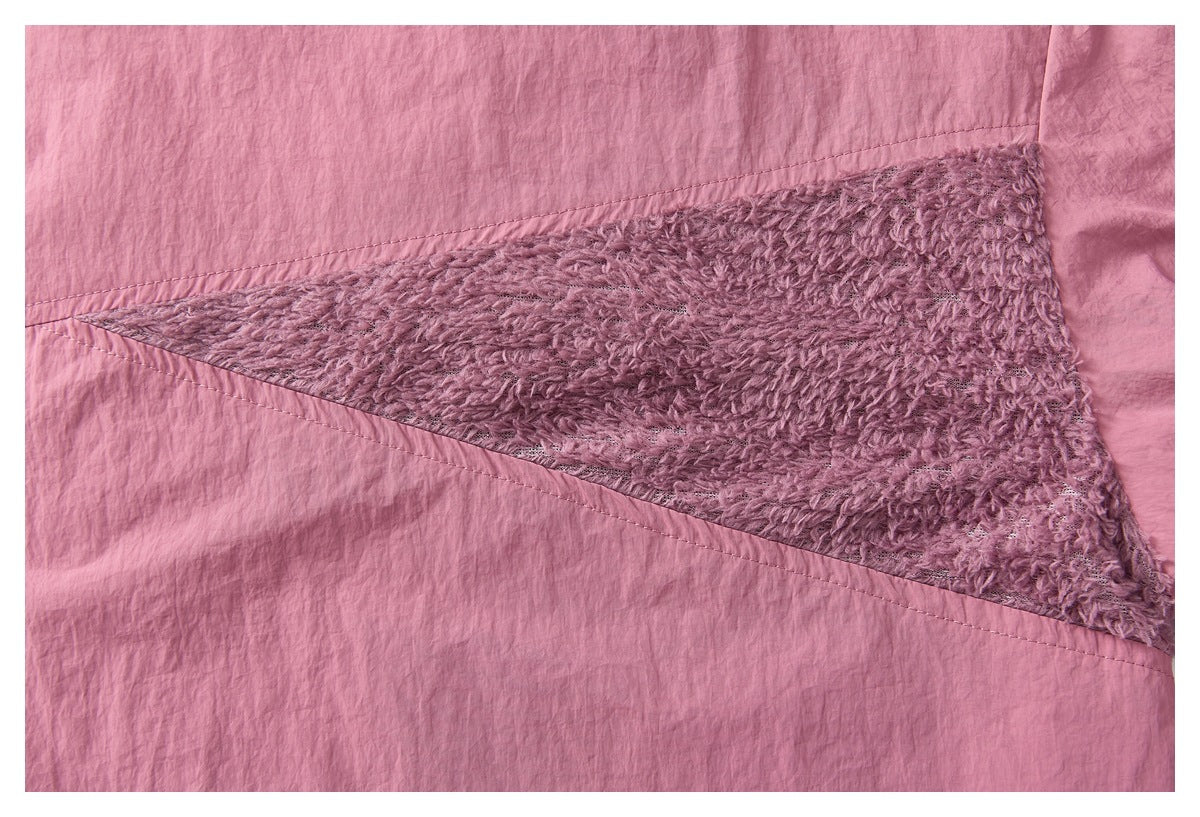 Close-up of a pink garment panel with a triangular inset of plush mauve fabric and visible stitching.