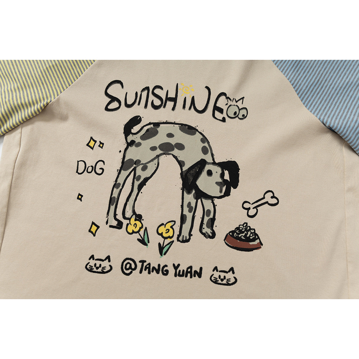 Close-up of a beige raglan shirt with a playful dog illustration and English lettering, plus striped sleeves.
