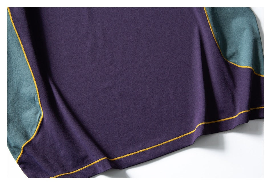 Close-up of the purple garment body and hem, with teal side panels and mustard-yellow seam stitching.