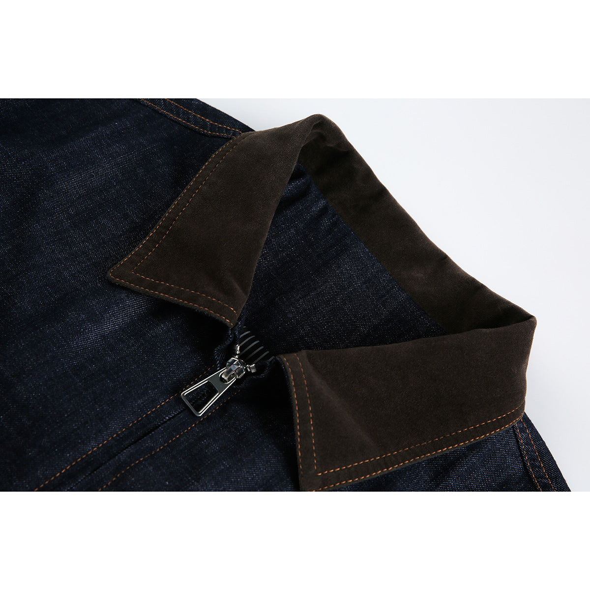 Close-up of a dark indigo jacket collar with brown panels, contrast stitching, and a silver zipper.