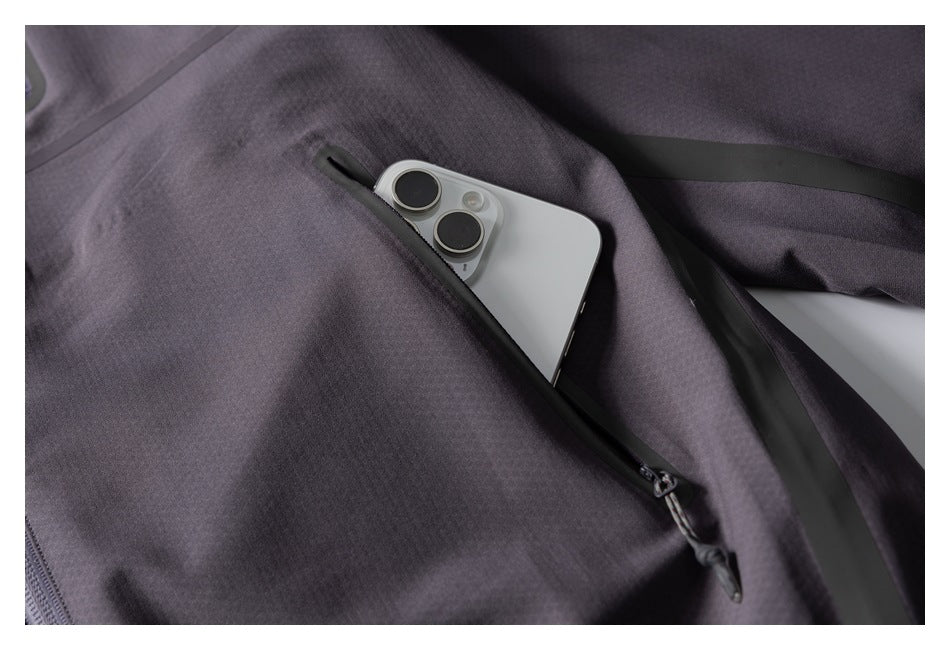 Close-up of a long zip pocket on the charcoal-gray pullover with a smartphone partly tucked inside.
