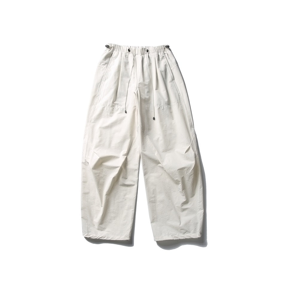 Off-white wide-leg parachute pants with drawcord elastic waistband, flat lay front view