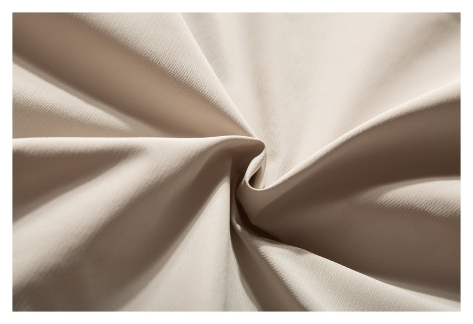 Close-up of light beige fabric gathered into a soft spiral fold, showing its fine surface texture.