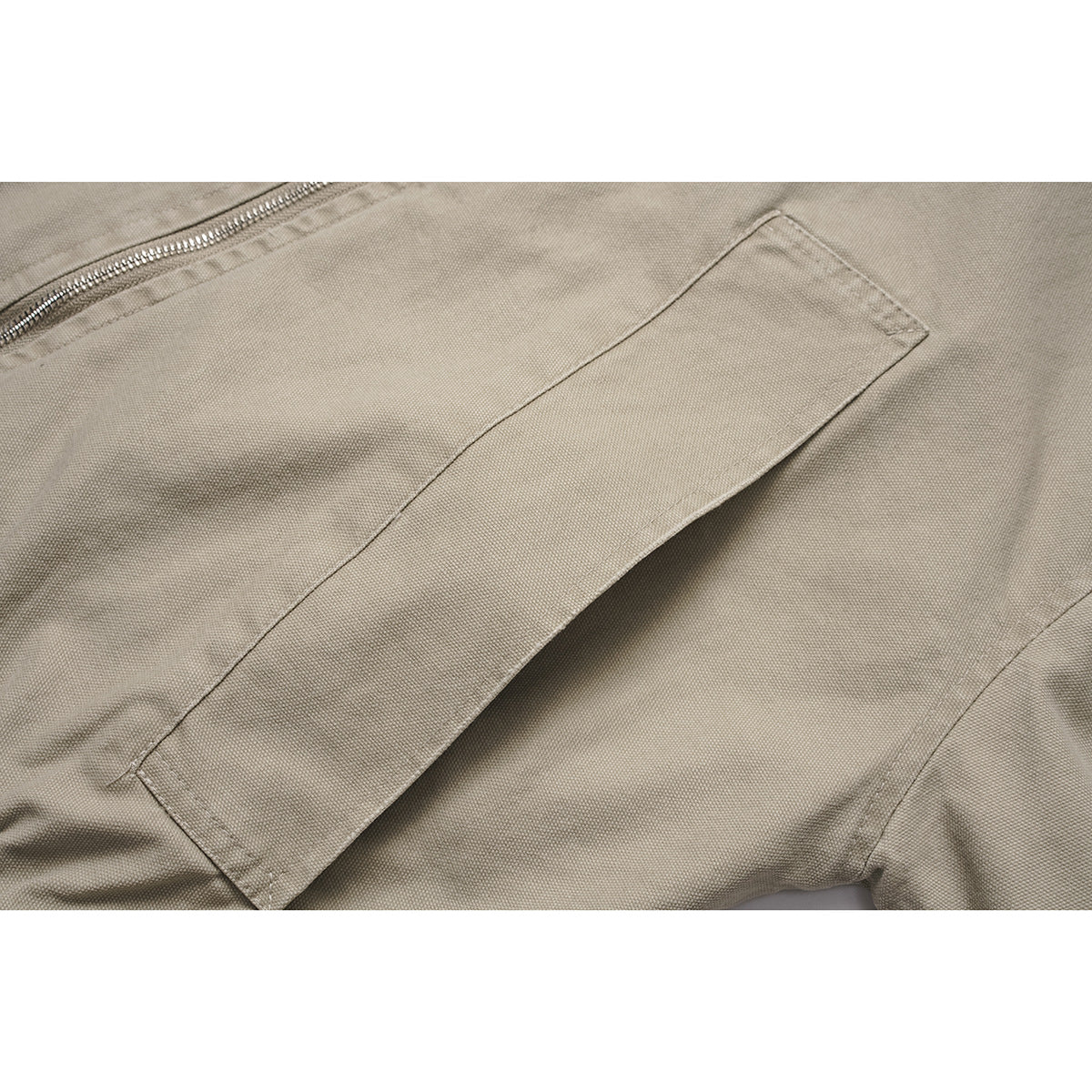 Close-up of a slanted pocket and zipper on the taupe jacket.