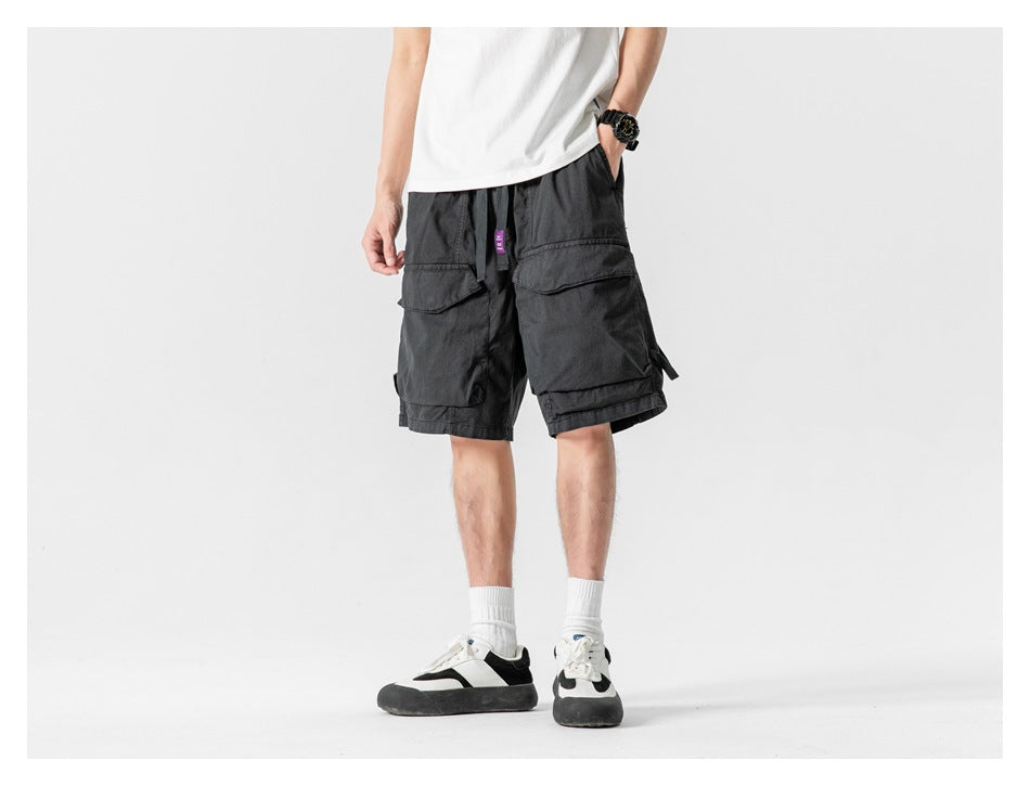 Front view of a model wearing black cargo shorts with large flap pockets and white sneakers.