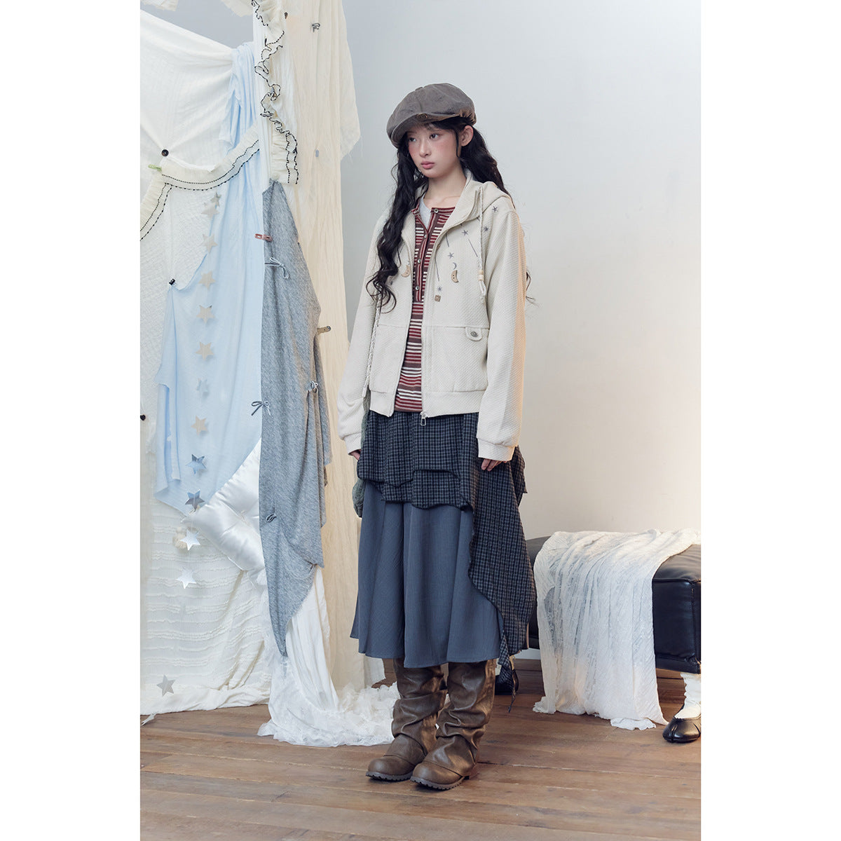 Full-length view of a model wearing an ivory celestial-print zip hoodie with a layered skirt and brown boots.