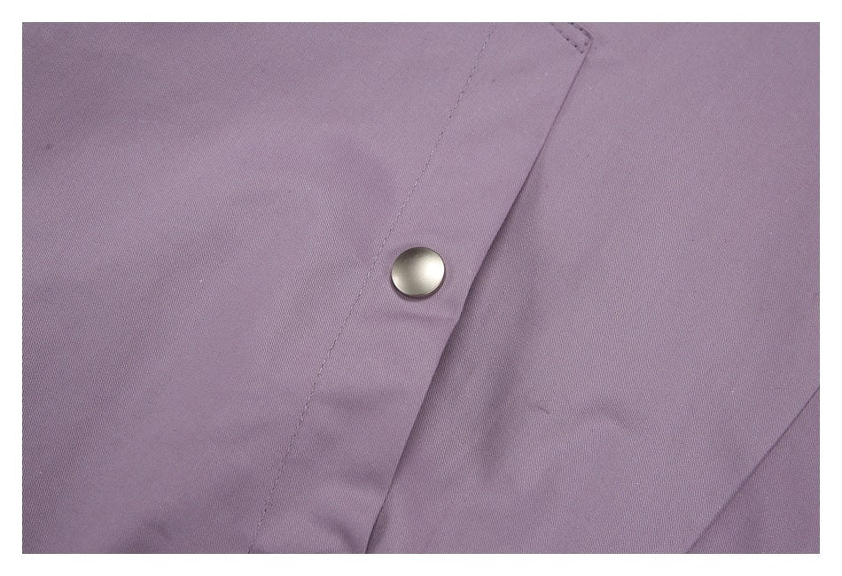 Close-up of a silver snap fastener on the mauve garment's placket.