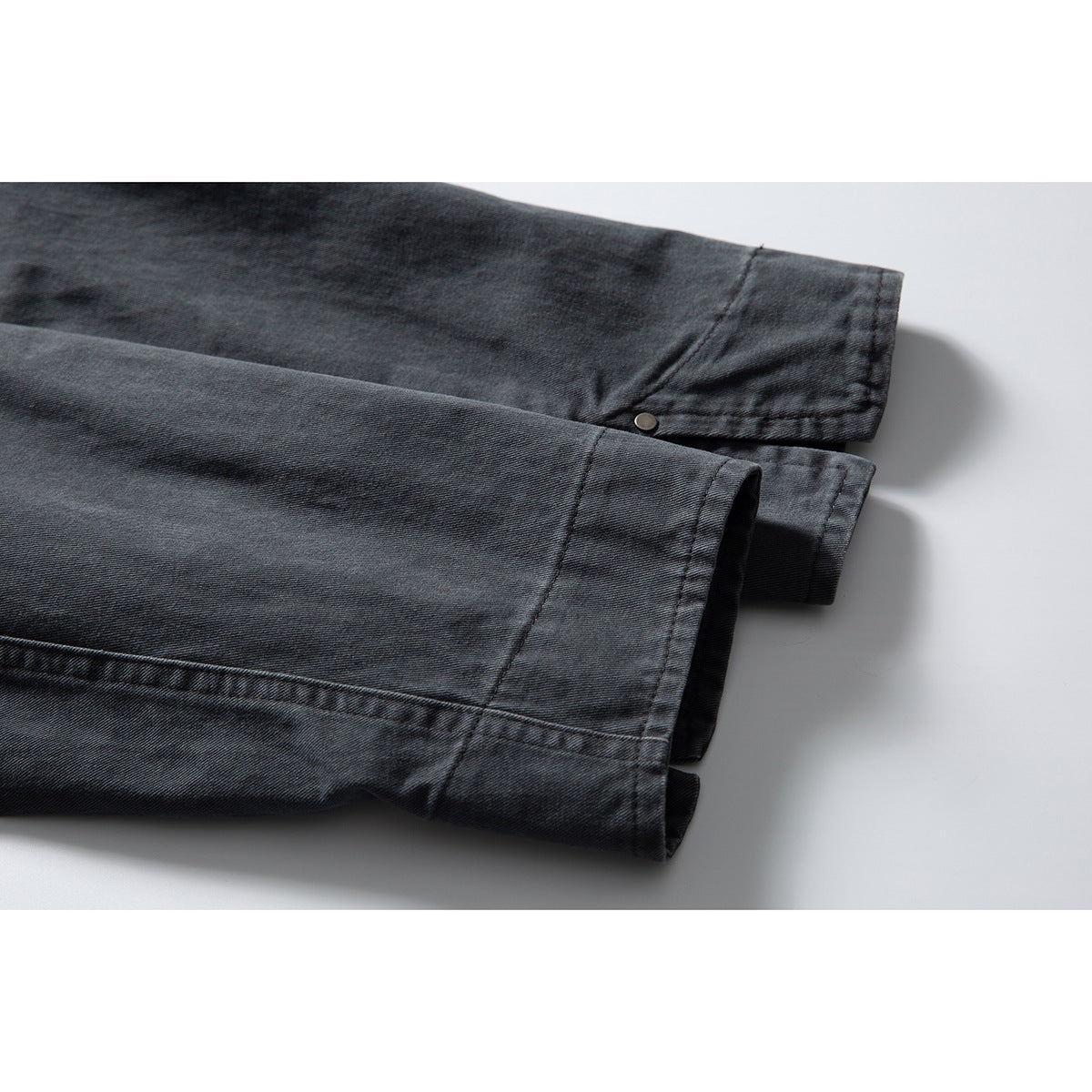 Close-up of two charcoal jacket sleeve cuffs with stitched hems and a small button detail.