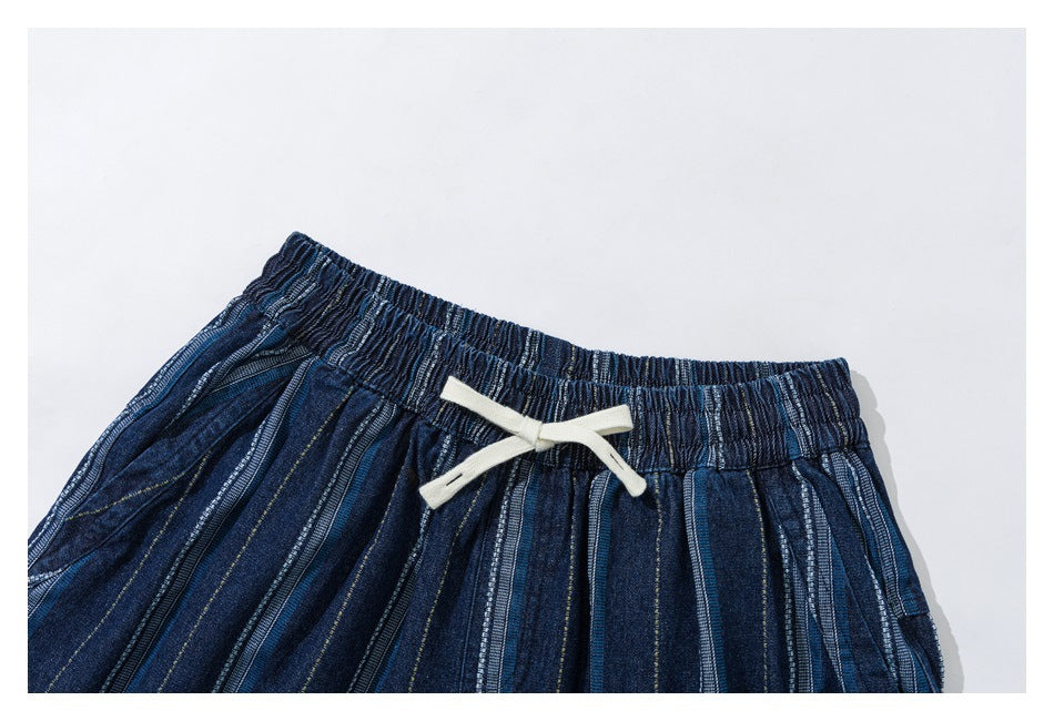 Flat lay of dark blue striped trousers showing the gathered elastic waist and cream drawstring.