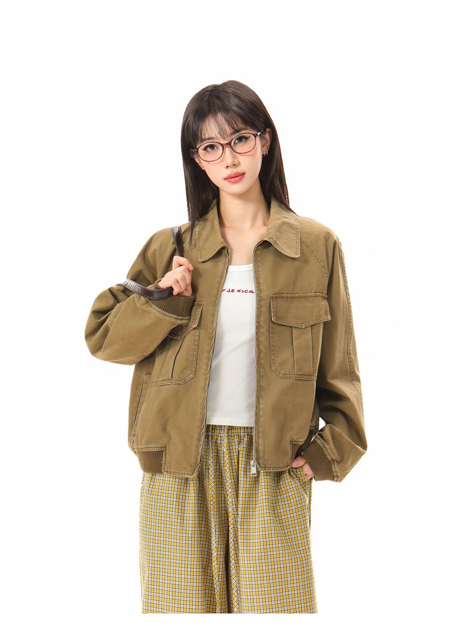 Model wearing an open tan utility jacket with two flap chest pockets over a white top and yellow plaid trousers.