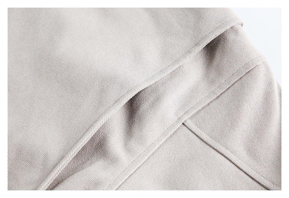 Close-up of the pale taupe-gray jacket's stitched panel seams and folded fabric edge.