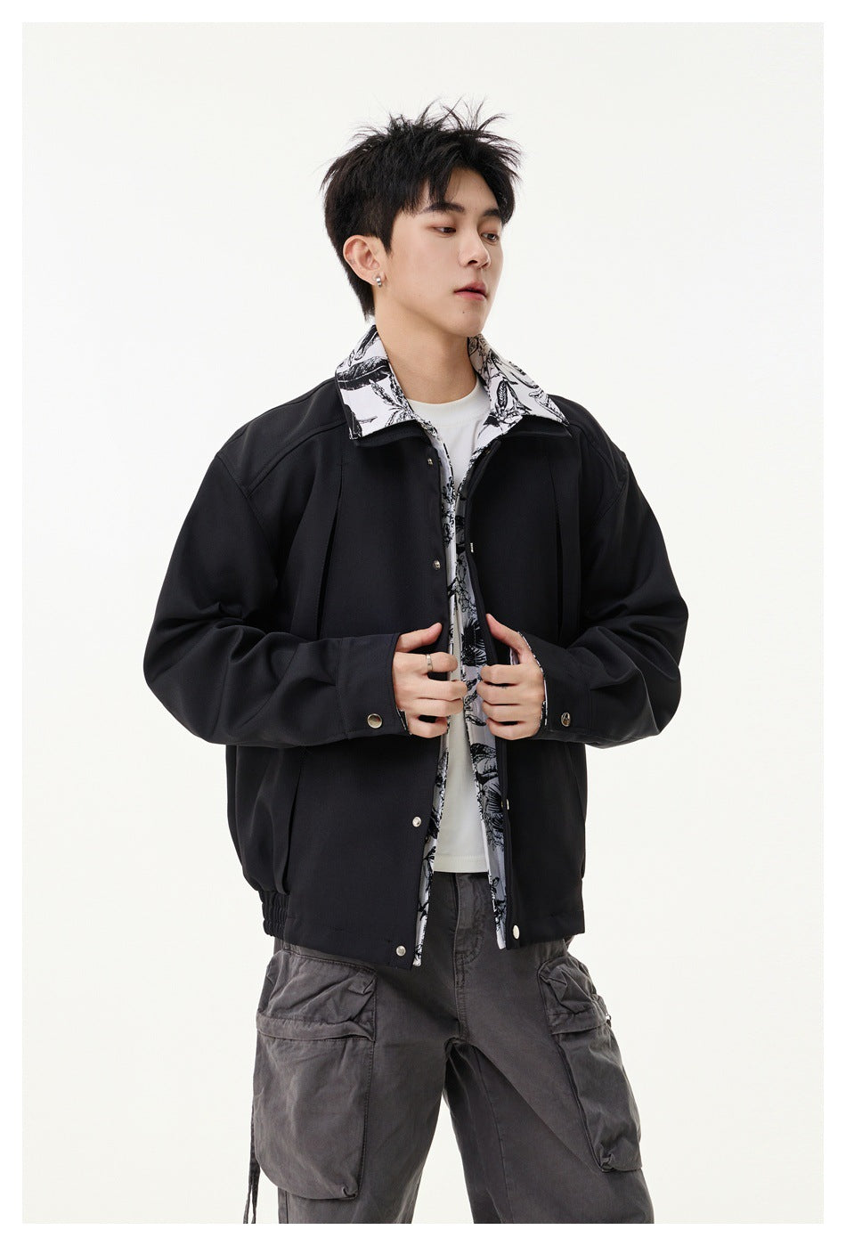 Model wearing a black snap-front jacket with a black-and-white floral-print collar and trim.