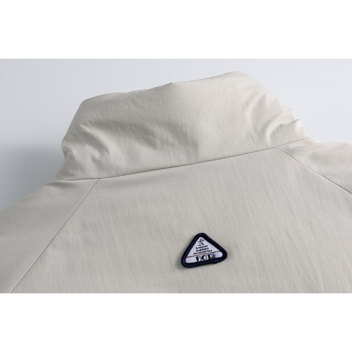 Close-up of the back yoke and small triangular patch on a light gray jacket.