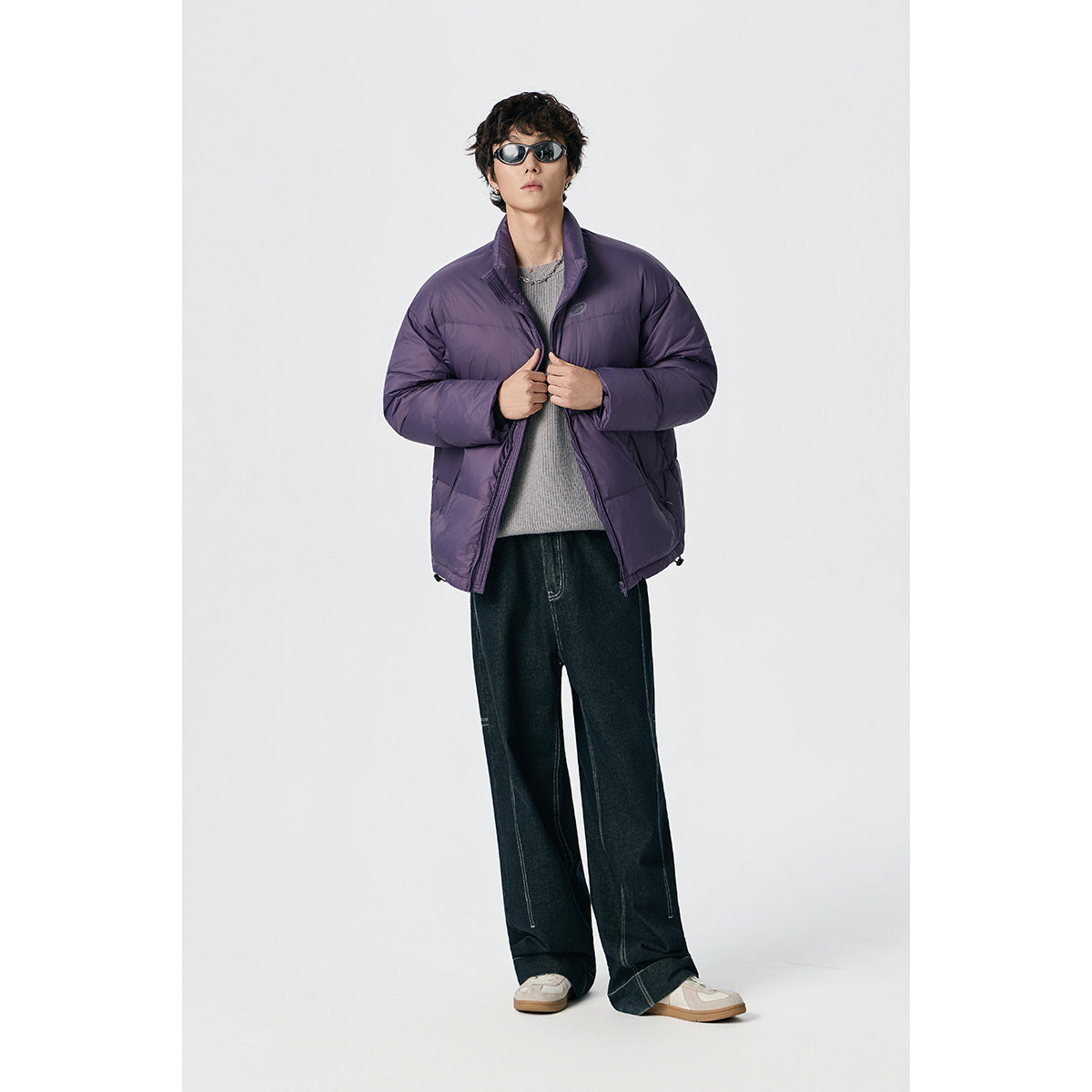 Model wearing an open purple quilted jacket with a stand collar and a gray sweater.