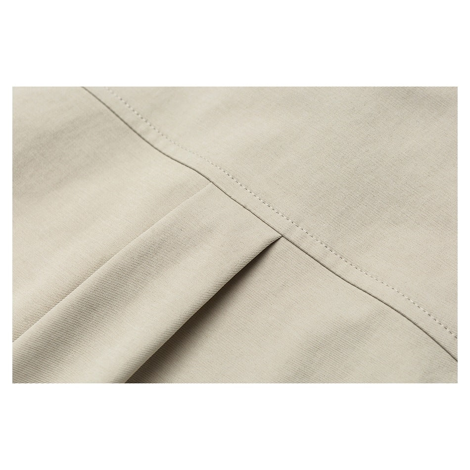 Close-up of beige garment fabric showing a stitched seam beside a folded fabric edge.