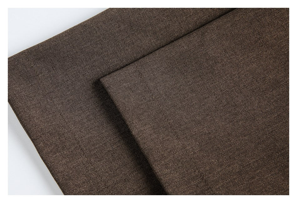 Close-up of overlapping dark brown woven garment panels and a folded edge.