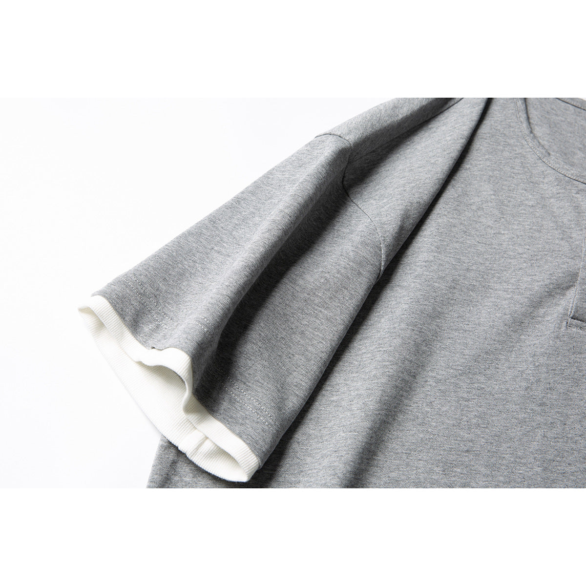 Close-up of a heather gray short sleeve with a contrasting white ribbed cuff.
