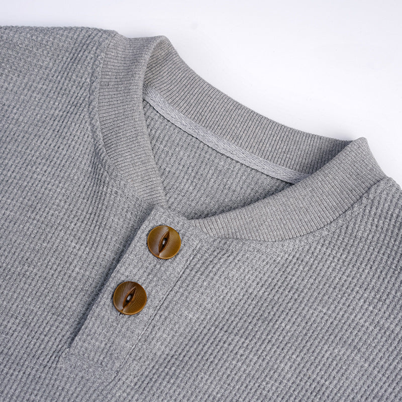 Close-up of a gray ribbed Henley shirt neckline with two brown buttons.