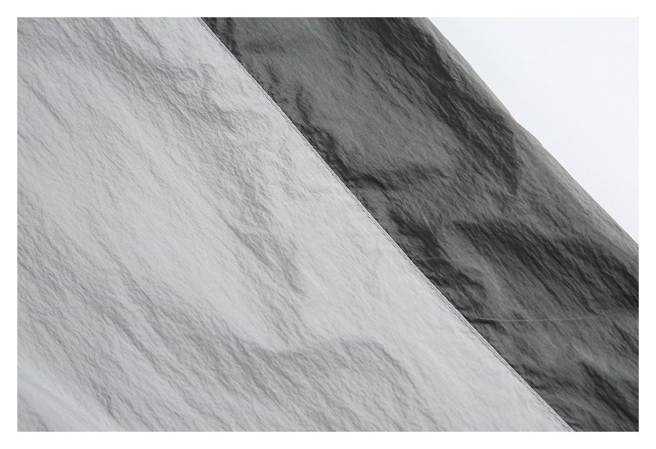 Close-up of a light gray jacket panel meeting a dark contrasting sleeve along a diagonal seam.