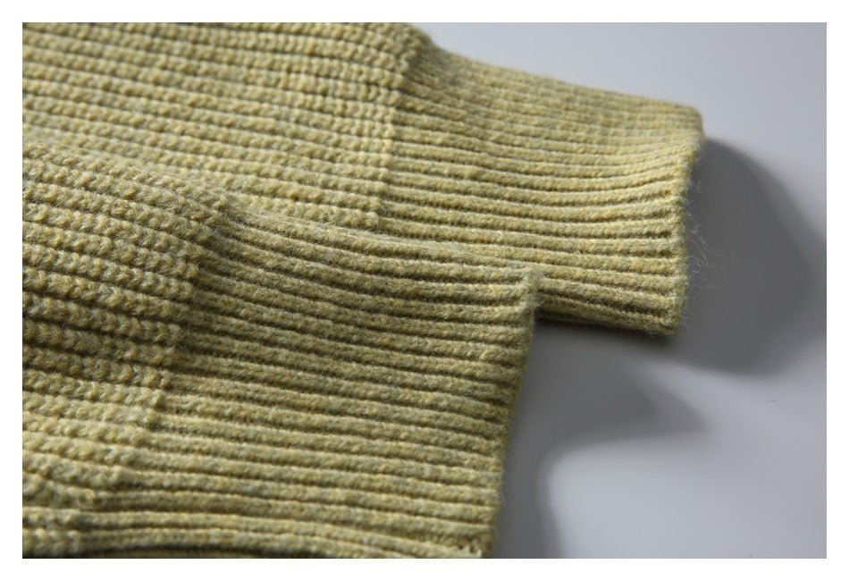 Close-up of a pale olive-beige ribbed knit sleeve cuff and adjoining garment fabric.