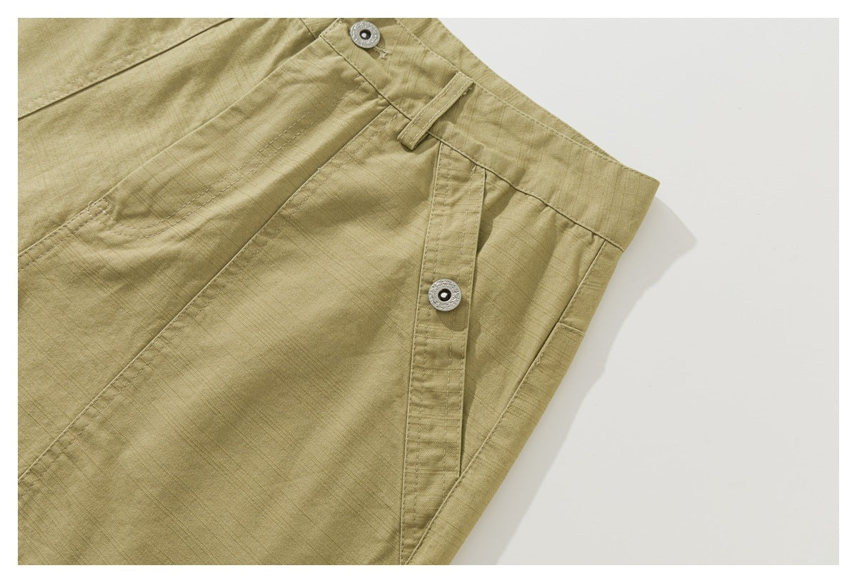 Close-up of khaki shorts showing an angled pocket opening with metal snap buttons and visible stitching.