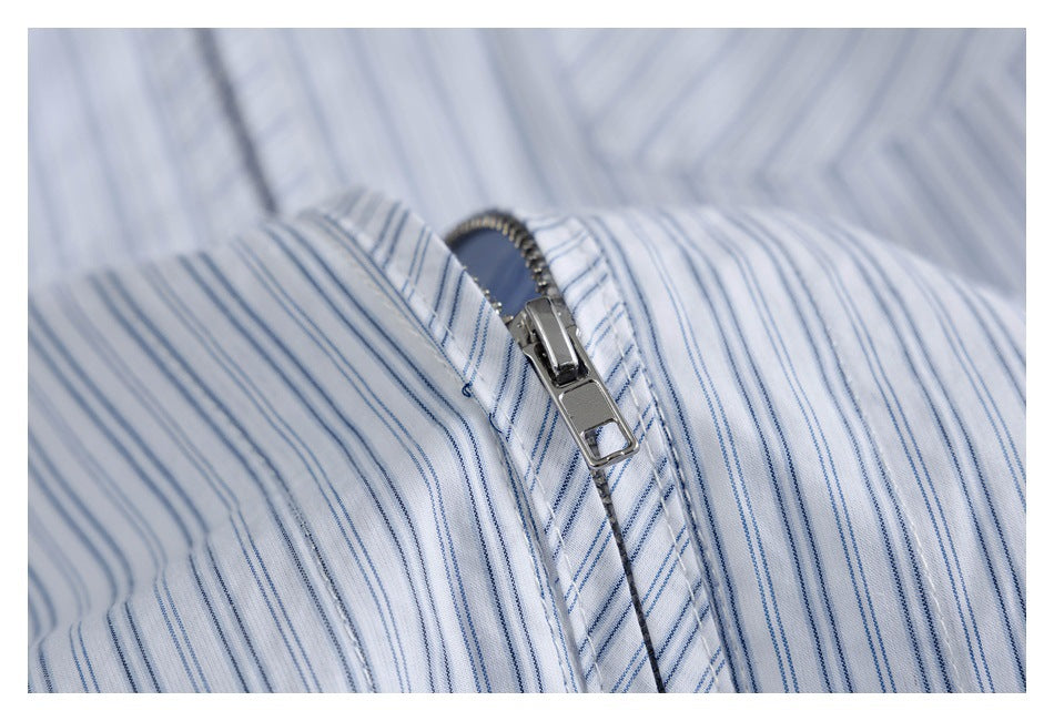 Close-up of a silver zipper on white fabric with thin blue vertical stripes.