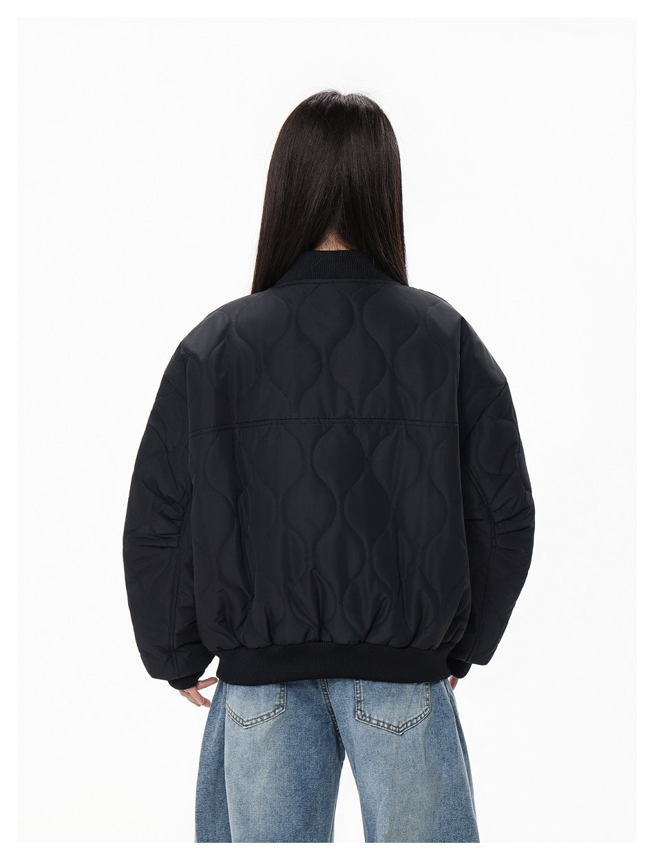 Back view of a woman wearing a black quilted bomber jacket with wavy quilting and ribbed collar and hem
