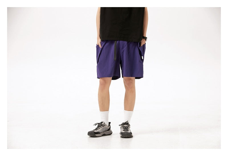 Cropped model wearing purple shorts with a drawstring and side pockets, shown from the front.