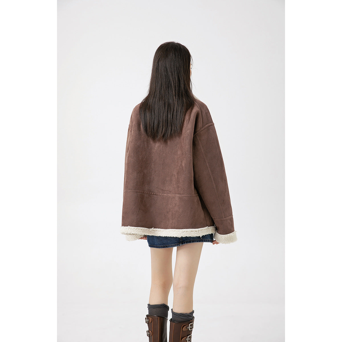 Rear view of a model wearing the brown jacket with cream fleece trim along the hem and cuffs.