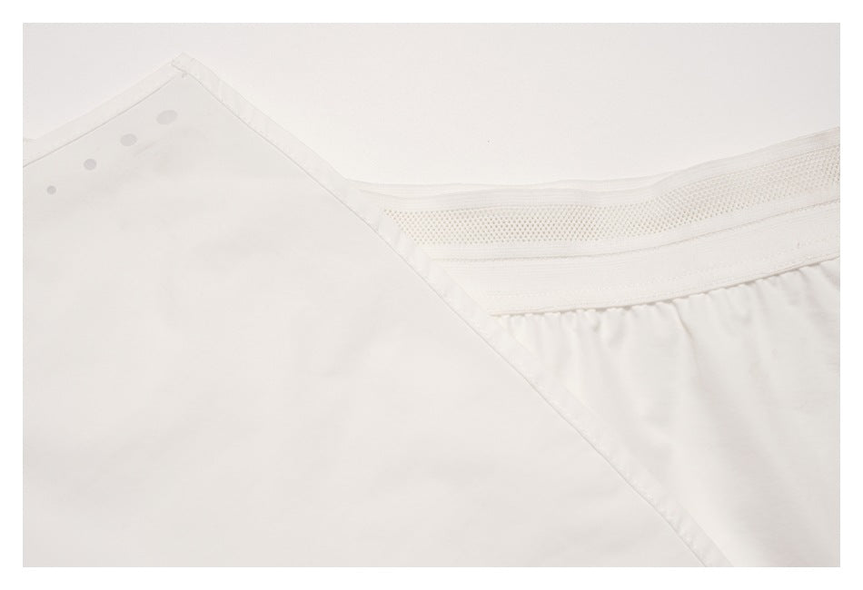 Close-up of a white garment showing a stitched edge and a wide perforated mesh-like band.