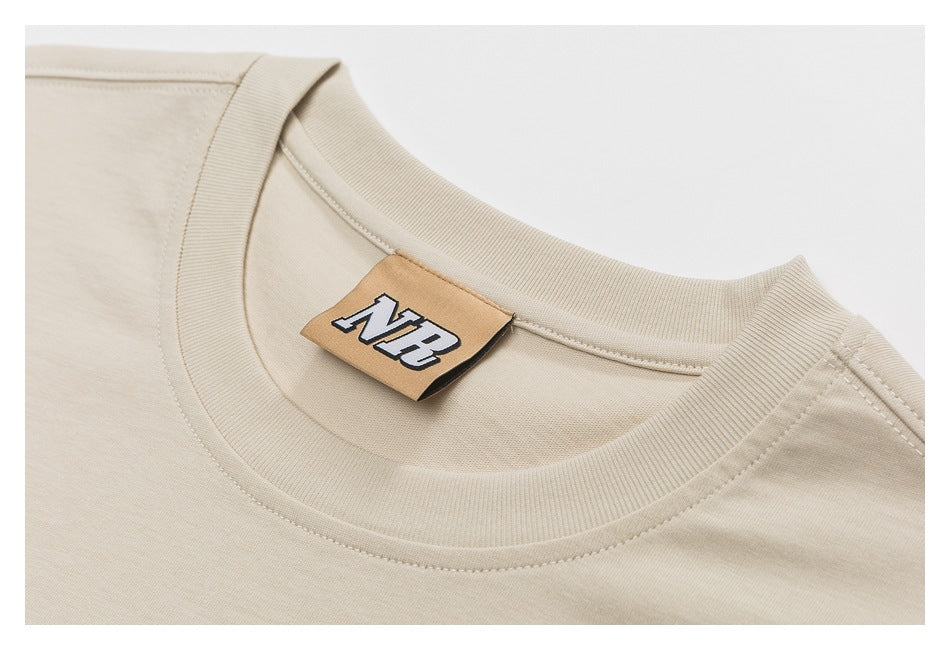 Close-up of a beige T-shirt crew neck and ribbed collar, with a tan NB label inside.