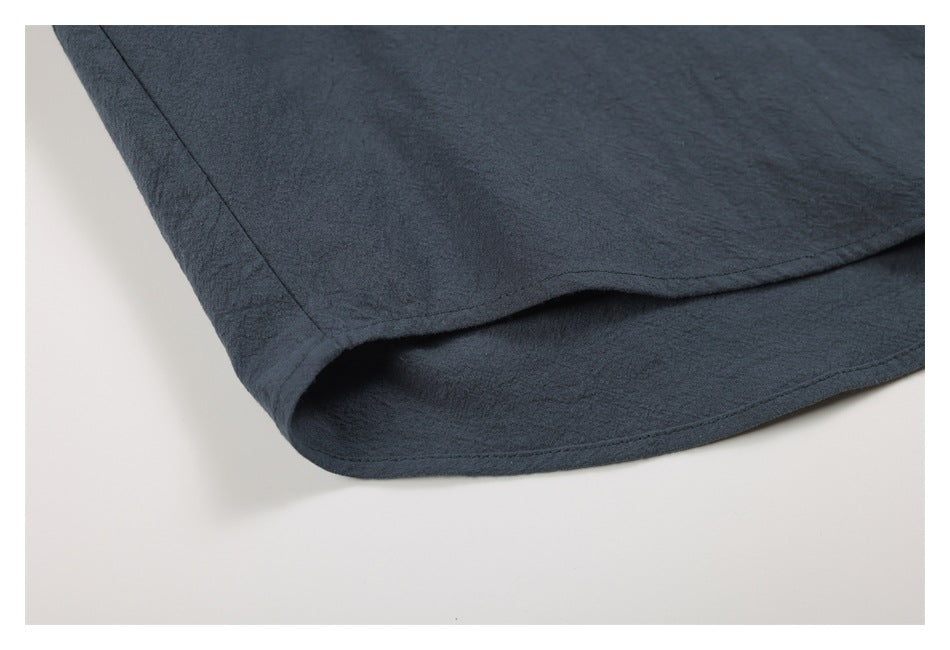 Close-up of the curved, double-stitched hem on a charcoal-blue garment.