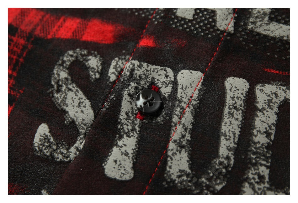 Close-up of a black button and distressed gray lettering printed over the shirt's plaid pattern.