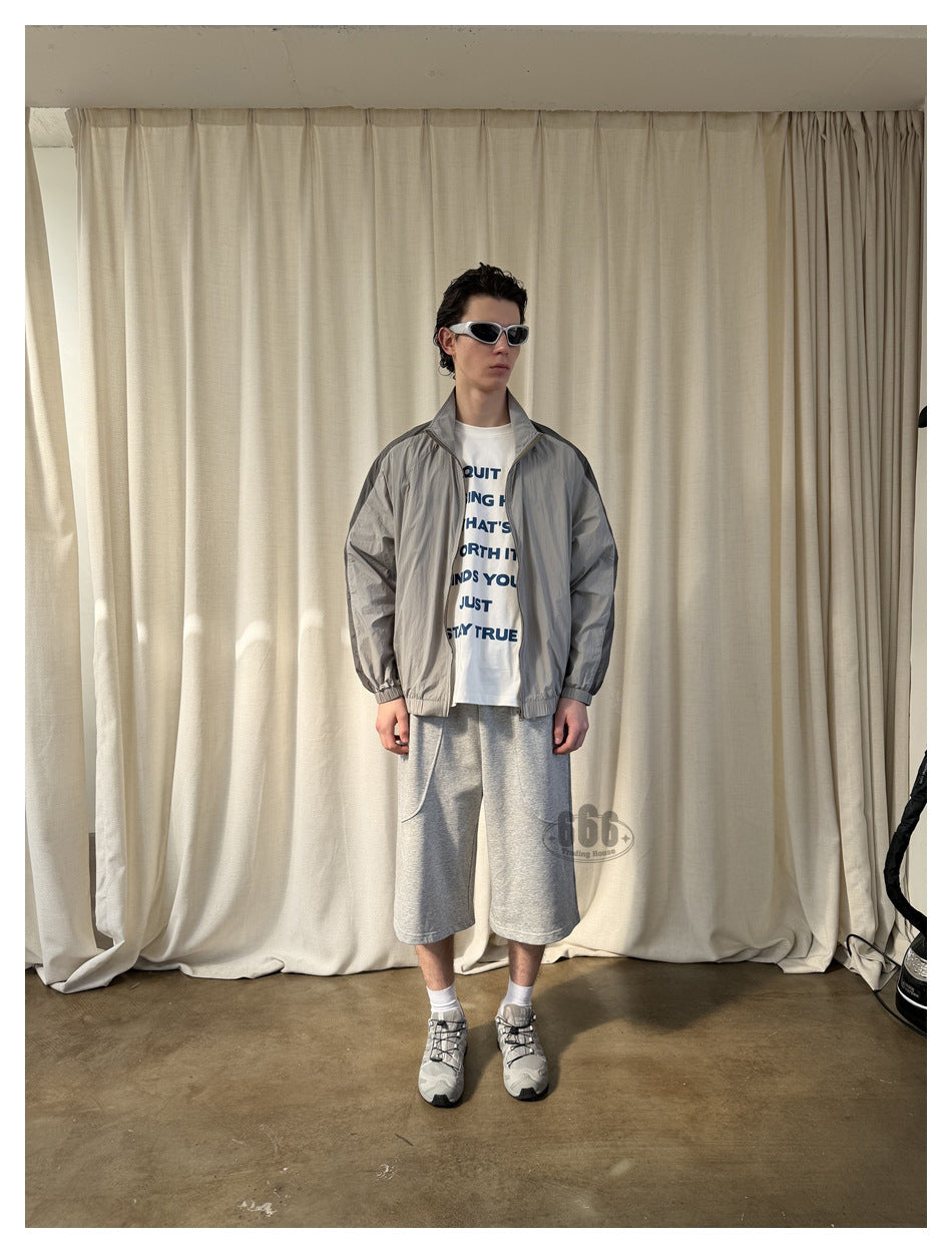 Model wearing heather gray knee-length shorts with a gray jacket, white graphic tee and gray sneakers, front view