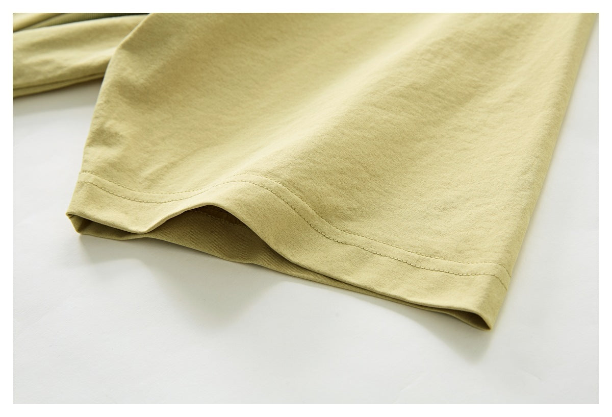 Close-up of the pale yellow T-shirt sleeve opening and its stitched hem.