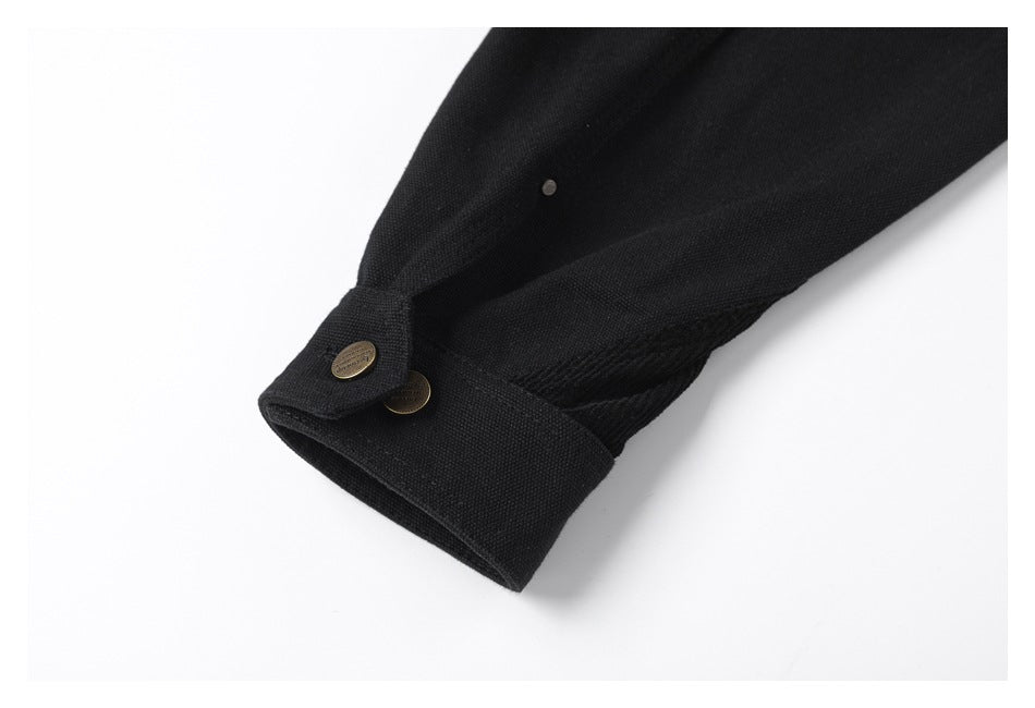 Close-up of a black sleeve cuff with a buttoned tab and a small metal detail on the sleeve.