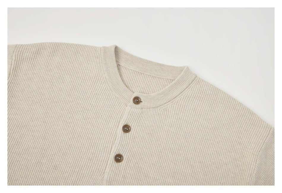 Close-up of a cream rib-knit cardigan neckline and front with three brown buttons.