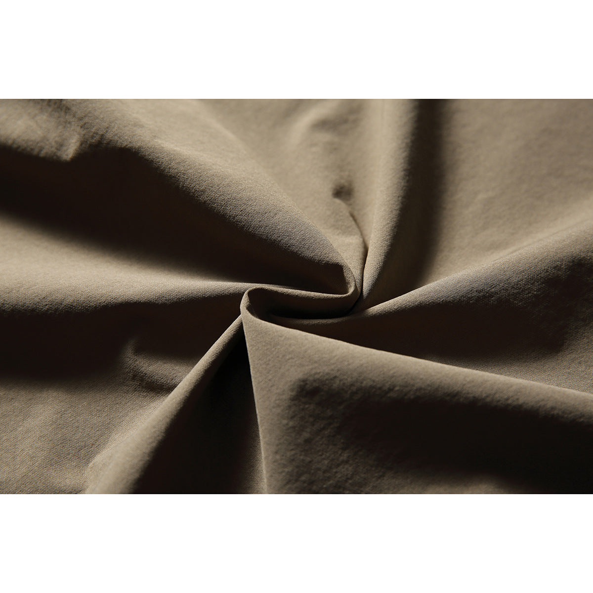 Close-up of taupe fabric gathered into folds, showing its surface texture.