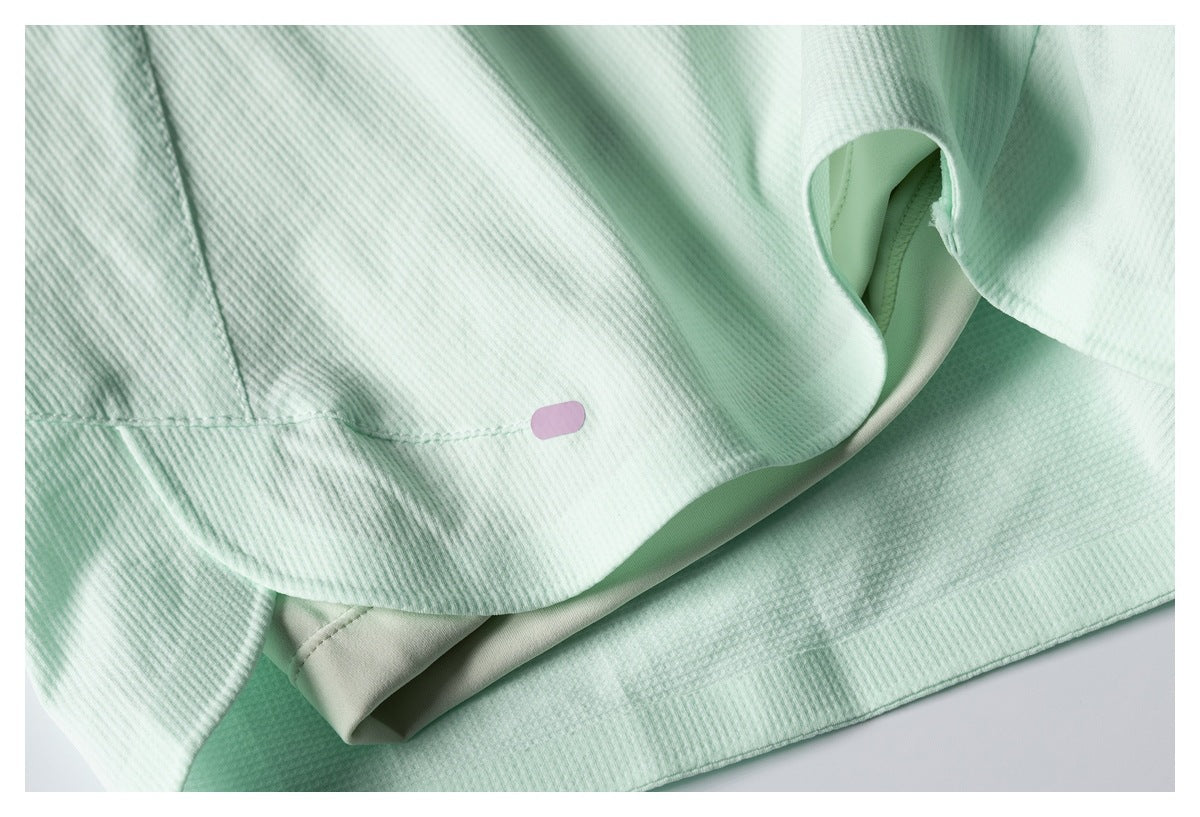 Pale mint textured garment with stitched seams and a small blank lilac oval accent.
