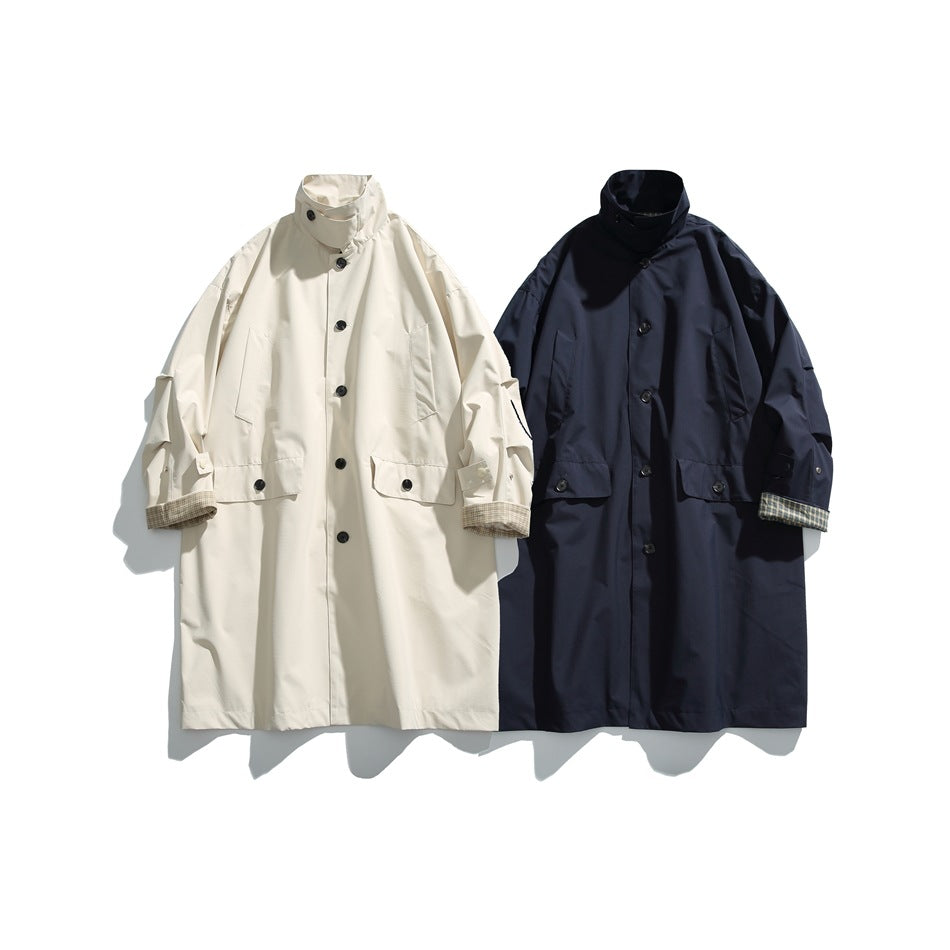 Two long coats shown side by side: one cream and one navy, both with high collars, button fronts and plaid cuffs.