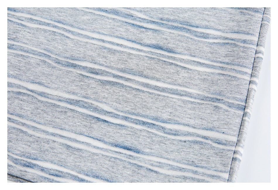 Close-up of gray knit fabric with irregular blue and white stripes and a finished edge.