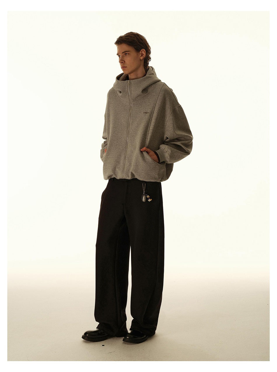 Full-length view of a model in an oversized gray zip hoodie, hands in pockets, with black wide-leg trousers