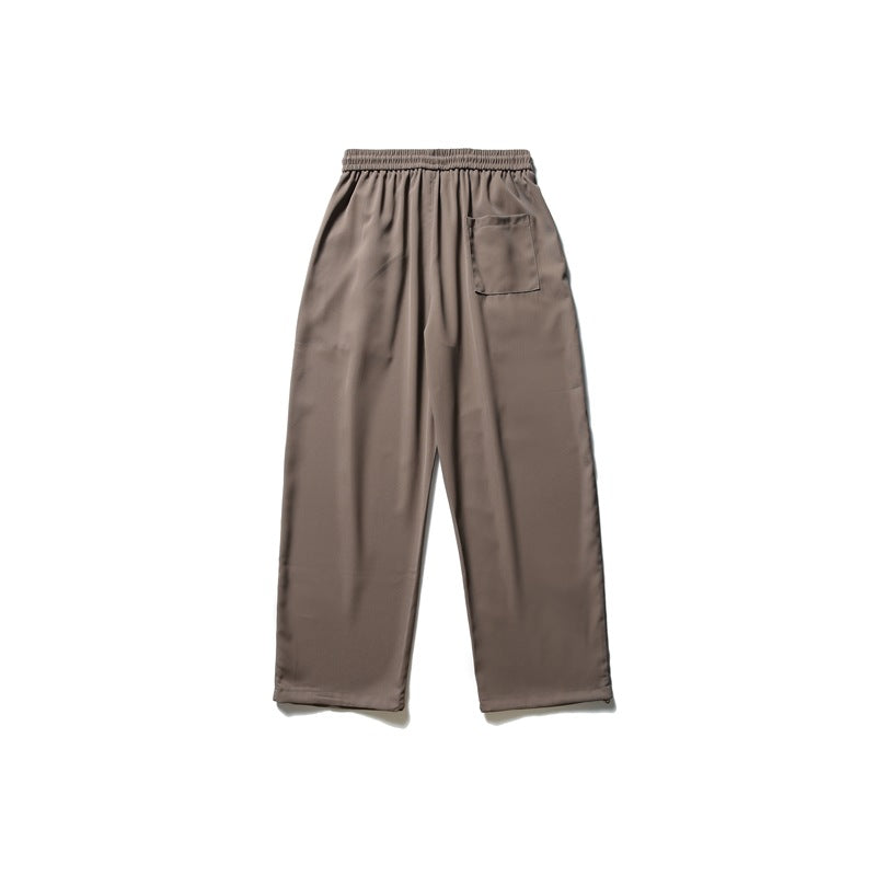 Back view of taupe wide-leg pants with an elastic waistband and a single rear patch pocket.
