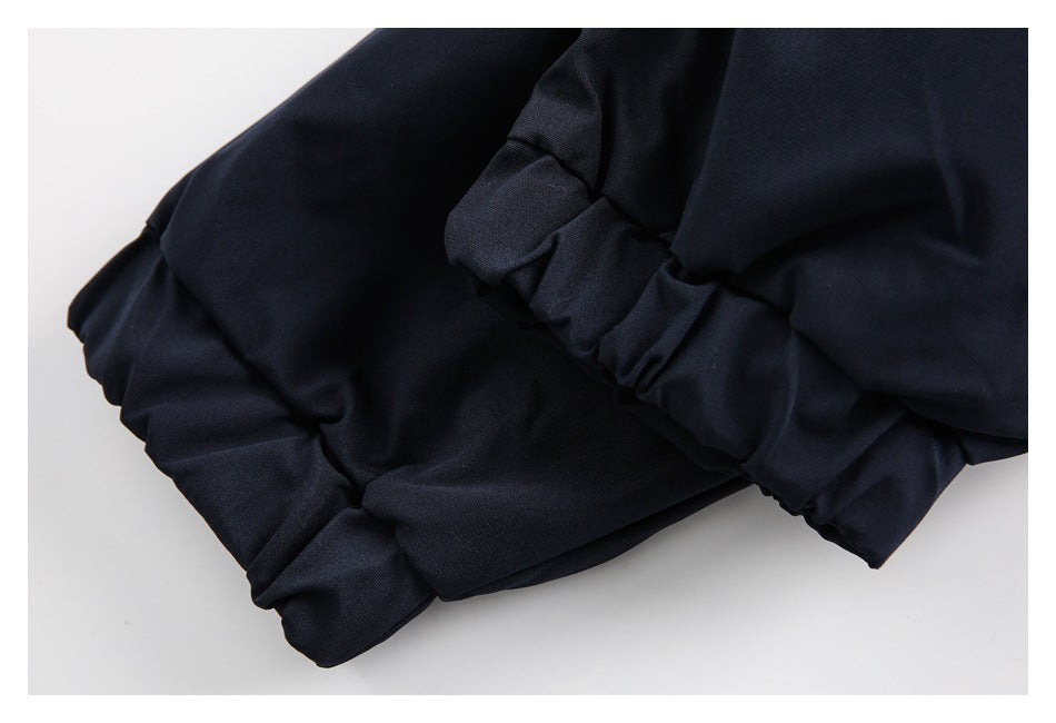 Close-up of gathered fabric and a cuff or hem on a dark navy garment.