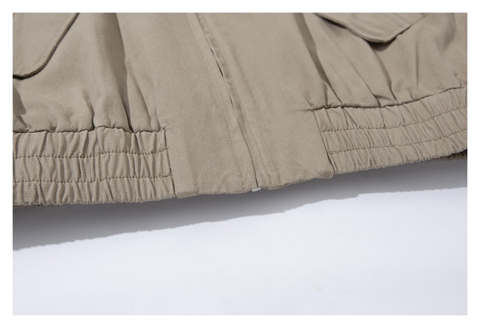 Close-up of a tan jacket’s gathered elastic hem and front closure.