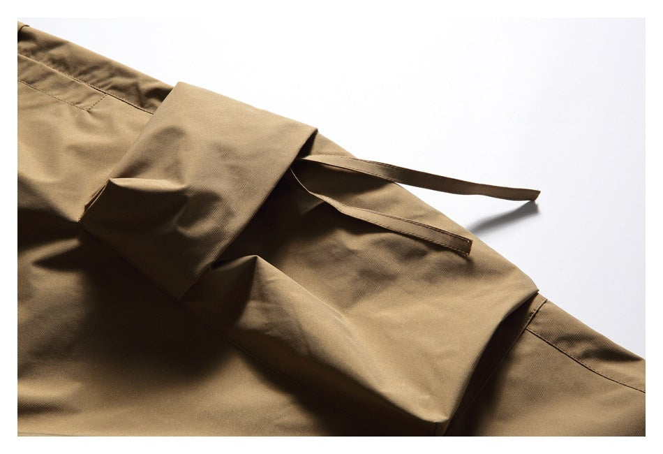Close-up of a tan cargo pocket flap and its narrow fabric fastening strap.