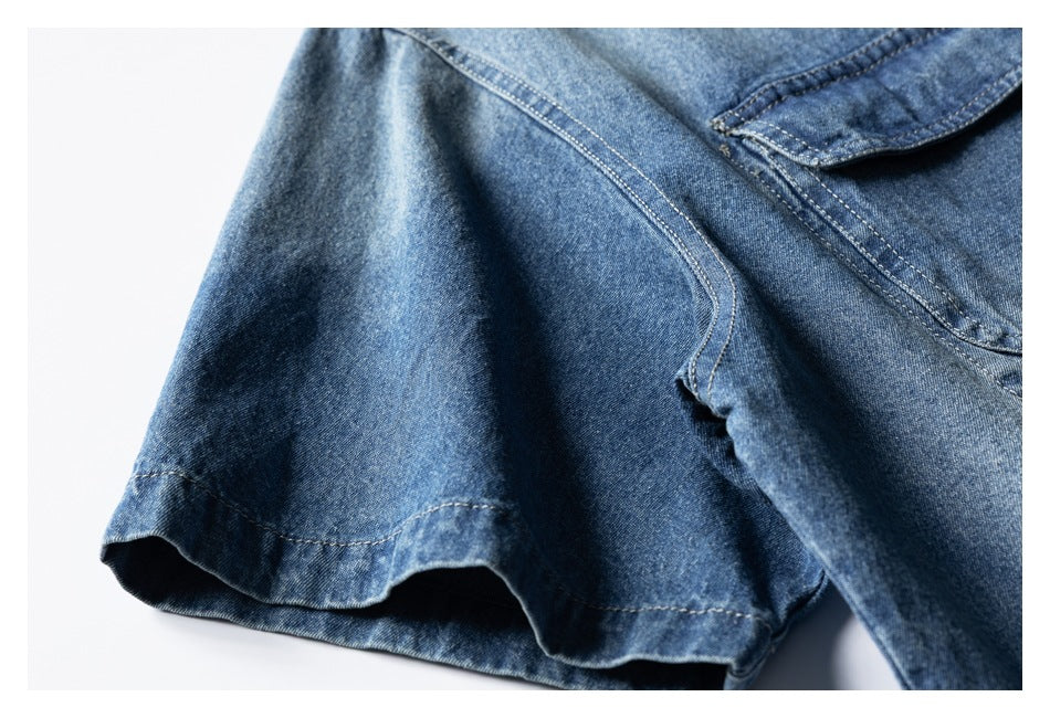 Close-up of a blue denim shirt sleeve, stitching, and overlapping collar edge.