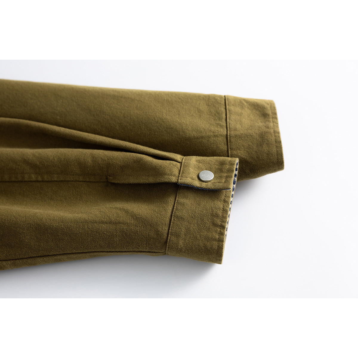 Close-up of an olive-brown jacket sleeve cuff with a silver snap tab.