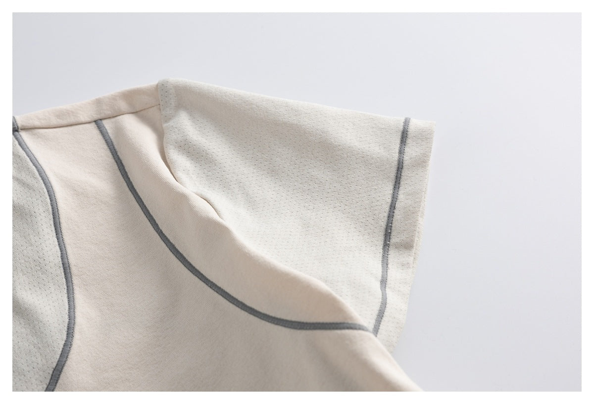 Close-up of an off-white shirt sleeve and curved gray piping beside perforated fabric panels.